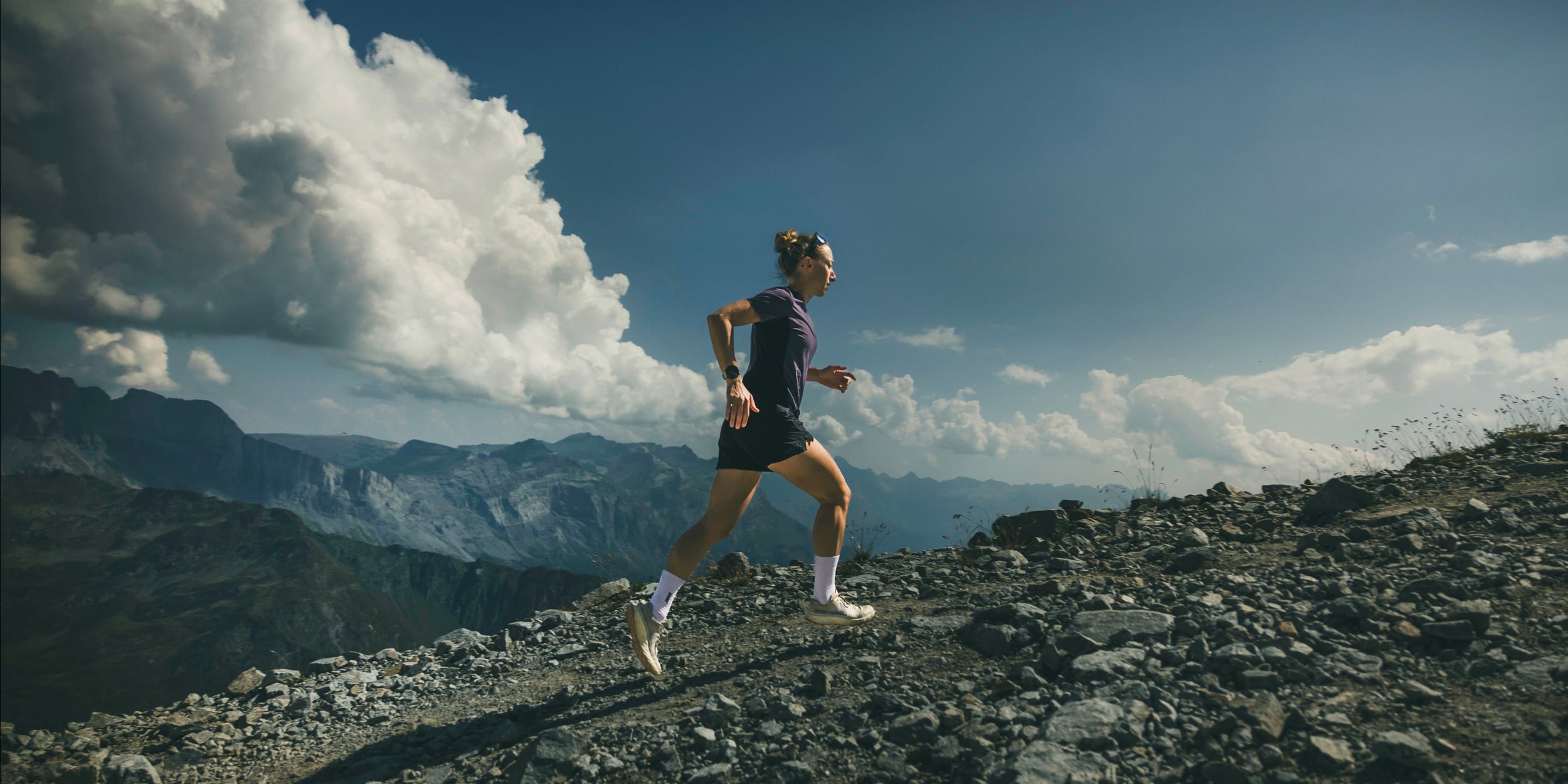 Femme qui court dans la nature avec un paysage de montagne et des vêtements WISE