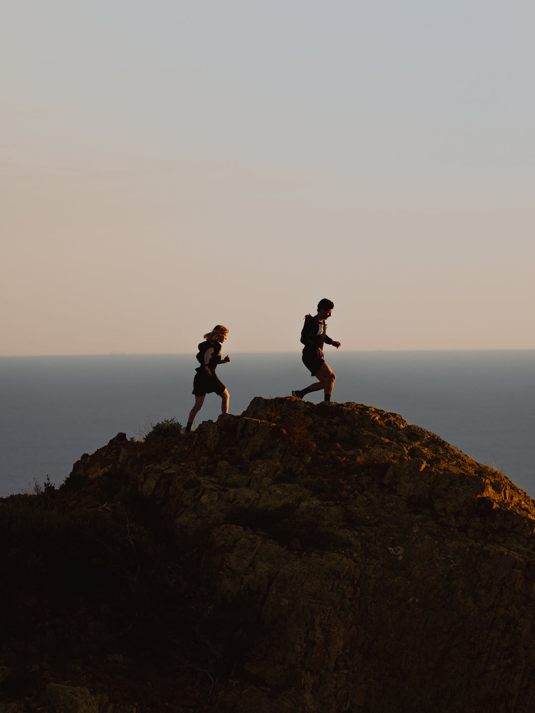 2 coureurs de trail sur le sommet d'une colline avec un fond d'océan