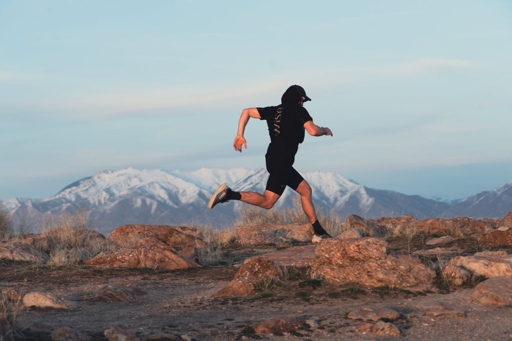 Image d'un coureur de trail, couché de soleil et avec une vue sur les montagnes eneigée